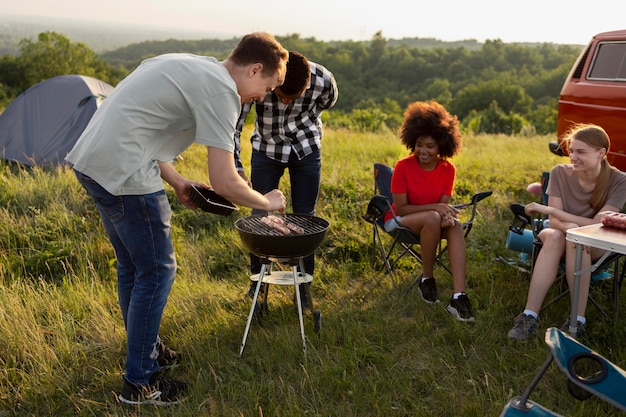 Amigos acampando junto con barbacoa tiro completo