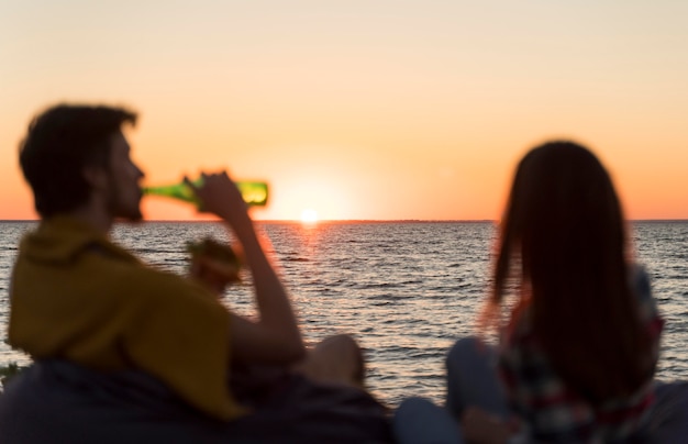 Amigos admirando la puesta de sol tomando una cerveza