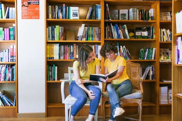 Foto gratuita amigos adolescentes leyendo el libro en sillas