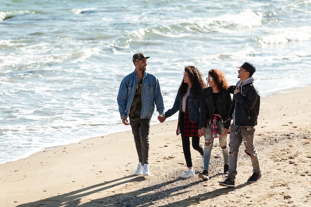 Foto gratuita amigos africanos felices caminando al aire libre en la playa