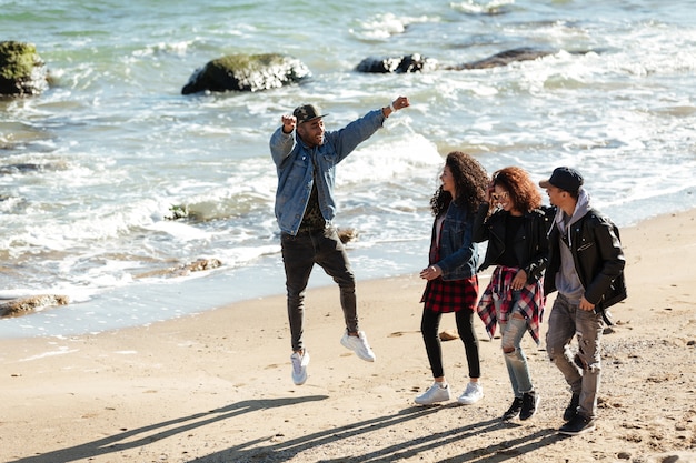 Foto gratuita amigos africanos felices caminando al aire libre en la playa