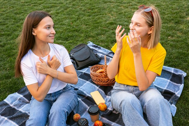 Amigos afuera que usan lenguaje de señas para comunicarse entre sí