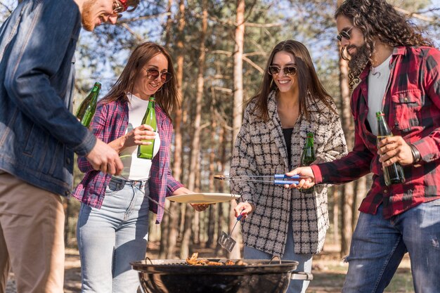 Amigos al aire libre tomando cerveza y haciendo una barbacoa