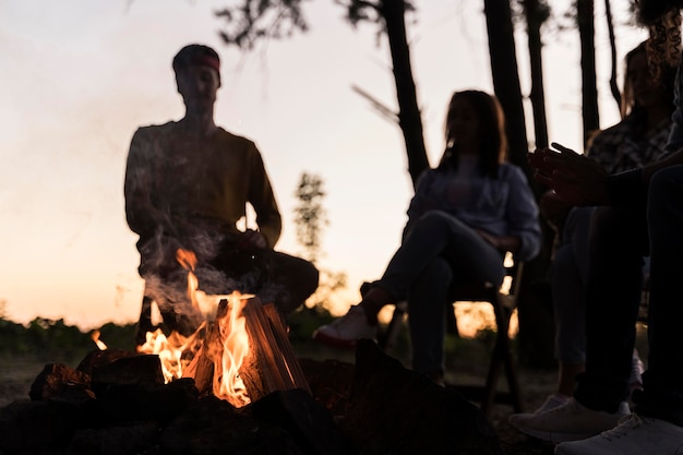 Amigos al atardecer reunidos alrededor de un fuego