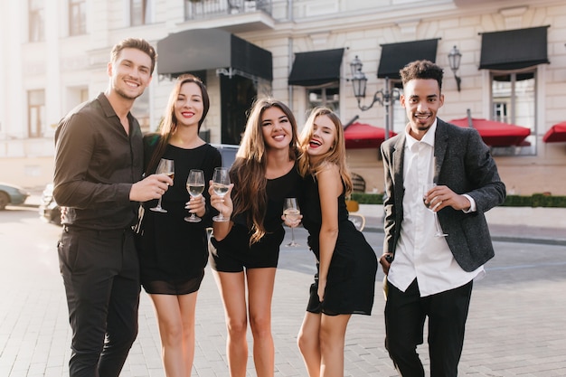 Amigos alegres bebiendo champán en la fiesta al aire libre