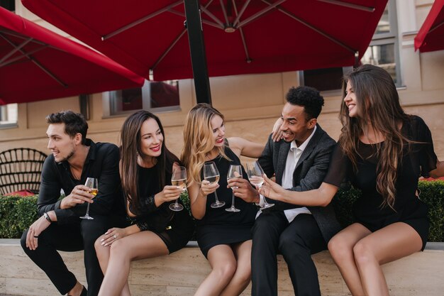 Foto gratuita amigos alegres bebiendo champán en la fiesta al aire libre