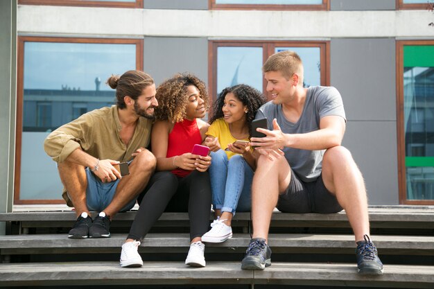 Amigos alegres felices leyendo noticias en las pantallas del teléfono