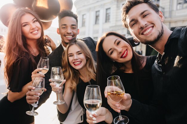 Amigos alegres con grandes sonrisas haciendo fotos durante la celebración