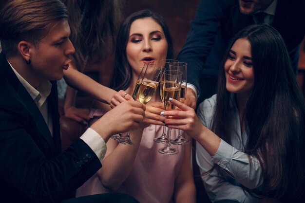 Amigos alegres hacen brindis y animan con copas de champán en una fiesta de cumpleaños. Lound celebración de un cumpleaños con champagne y brindis.