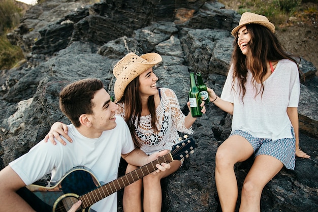 Amigos alegres en la playa con guitara