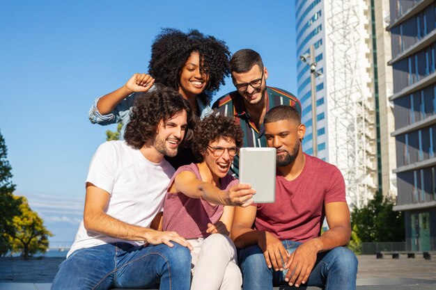 Amigos alegres que usan tableta para videollamadas grupales