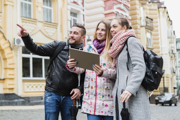 Amigos alegres con tableta en la calle