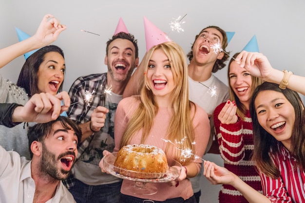 Amigos alegres con tarta de cumpleaños