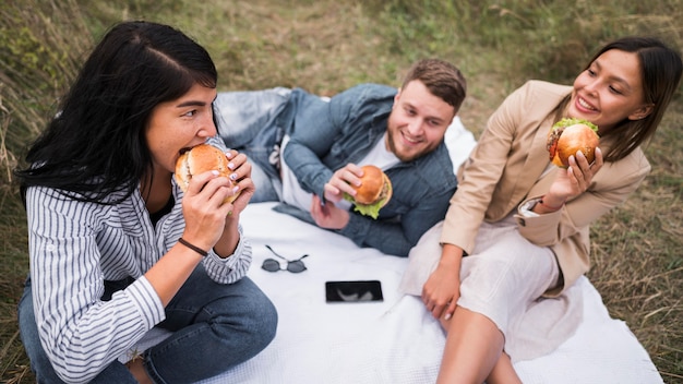 Amigos de alto ángulo comiendo hamburguesas