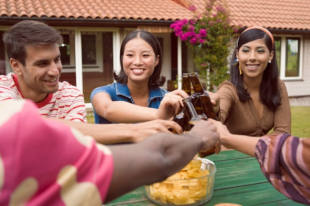 Foto gratuita amigos de alto ángulo tintineando botellas