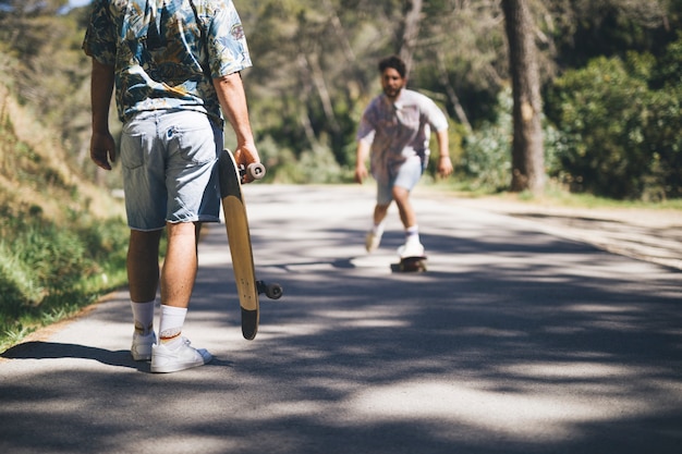 Amigos andar en monopatín en el camino forestal