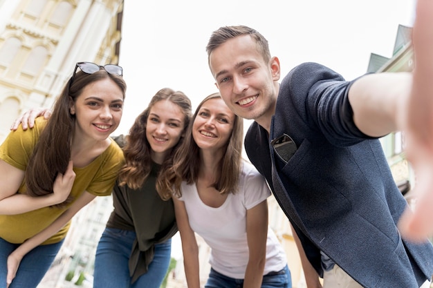 Foto gratuita amigos de ángulo bajo sonriente tomando selfie