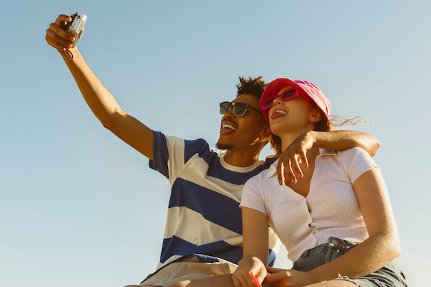 Amigos de ángulo bajo sonriente tomando selfie