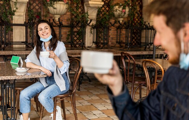 Amigos animando con tazas de té respetando la distancia social