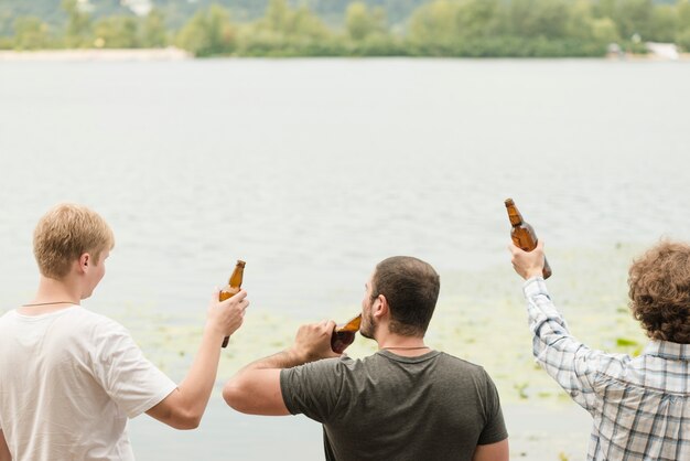 Amigos anónimos disfrutando de cerveza cerca del agua