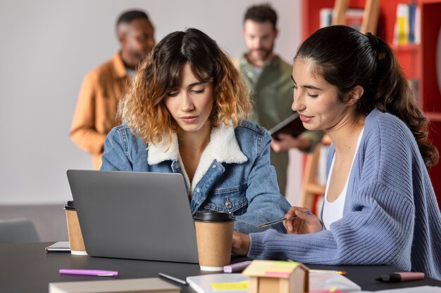 Amigos aprendiendo juntos de notas y laptop