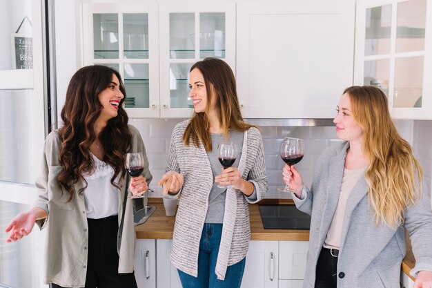 Amigos bebiendo vino y hablando en la cocina