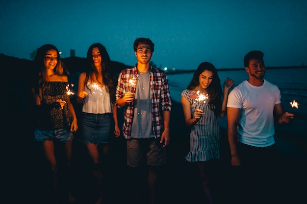 Foto gratuita amigos con bengalas en una playa de noche