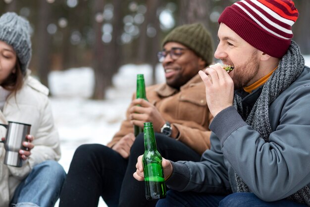 Amigos con botellas y comida en la naturaleza.