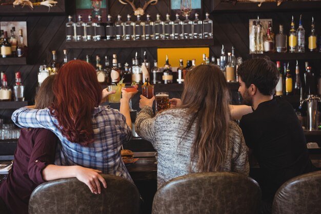 Amigos brindando con cerveza y copas de cóctel en el bar