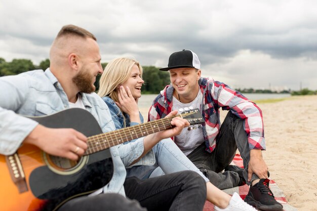 Amigos cantando y tocando la guitarra en la playa