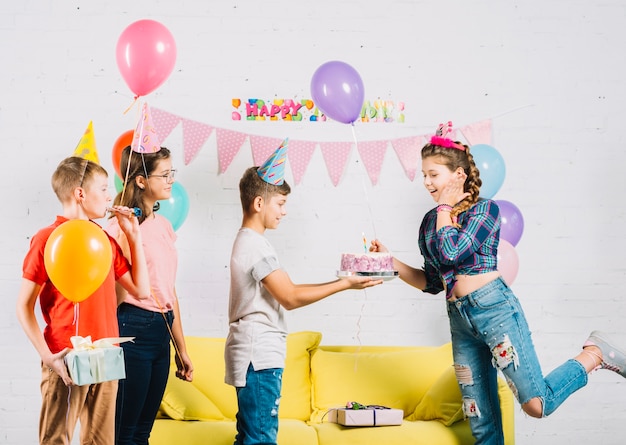 Amigos celebrando cumpleaños de niña con pastel