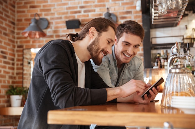 Foto gratuita amigos cerca del bar mirando el teléfono