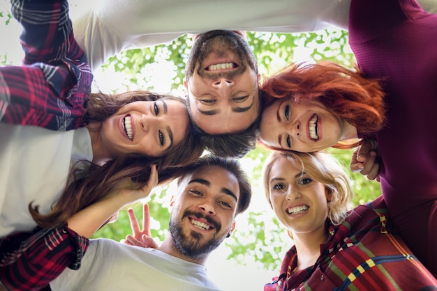 Amigos en círculo con las cabezas juntas haciendo una foto desde abajo