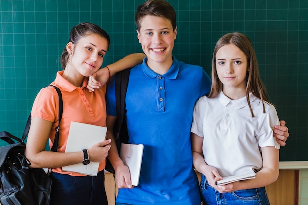 Foto gratuita amigos del colegio posando delante de la pizarra