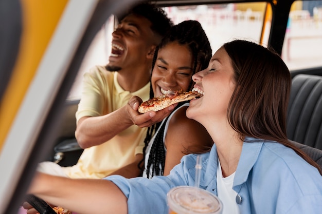 Amigos con comida en auto plano medio