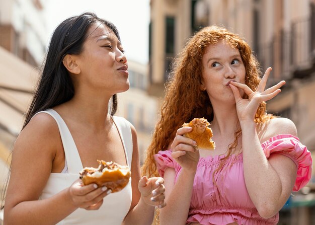 Amigos comiendo juntos algo de comida en la calle