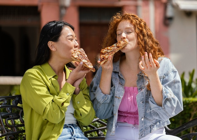 Amigos comiendo juntos algo de comida en la calle