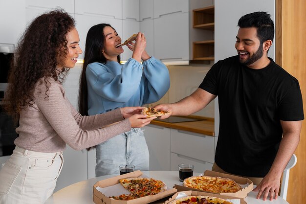 Amigos comiendo pizza en casa juntos