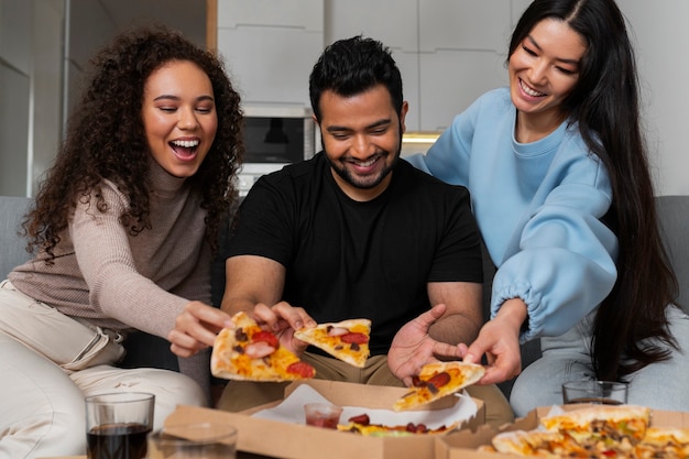 Amigos comiendo pizza en casa juntos