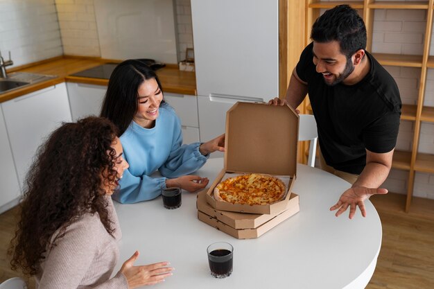 Amigos comiendo pizza en casa juntos