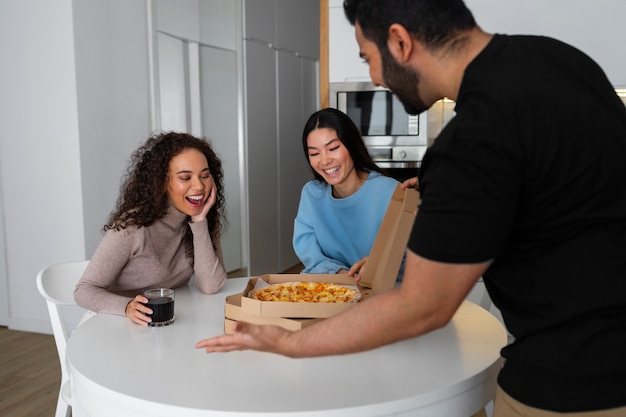 Amigos comiendo pizza en casa juntos