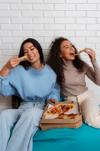 Amigos comiendo pizza en casa juntos