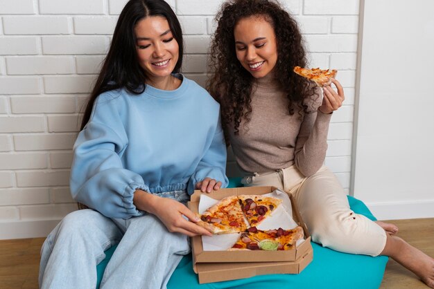 Amigos comiendo pizza en casa juntos