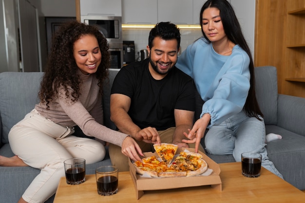 Amigos comiendo pizza juntos en casa