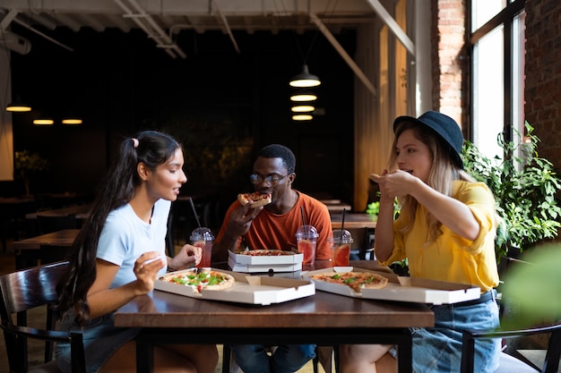 Amigos comiendo pizza plano medio