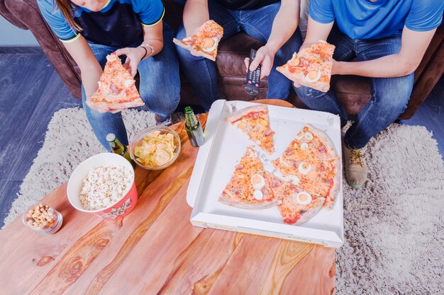 Amigos comiendo pizza y viendo el fútbol