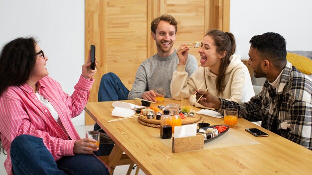 Amigos comiendo sushi en casa plano medio