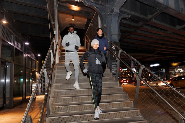 Amigos corriendo por las escaleras por la noche en la ciudad