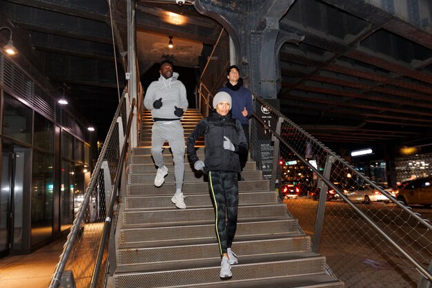 Amigos corriendo por las escaleras por la noche en la ciudad