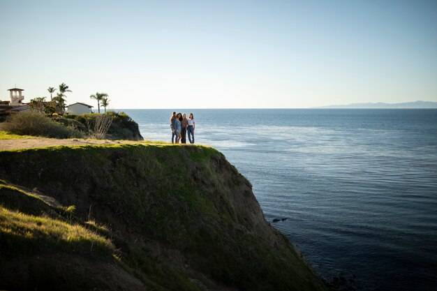 Amigos en la costa mirando al océano tiro largo